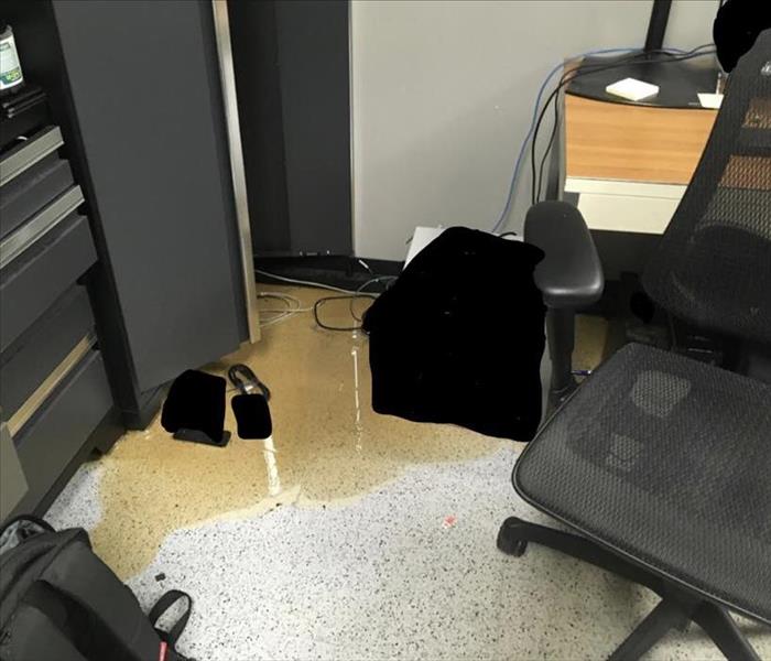 Floor in an office with water in a corner area that looks rusty yellow. 